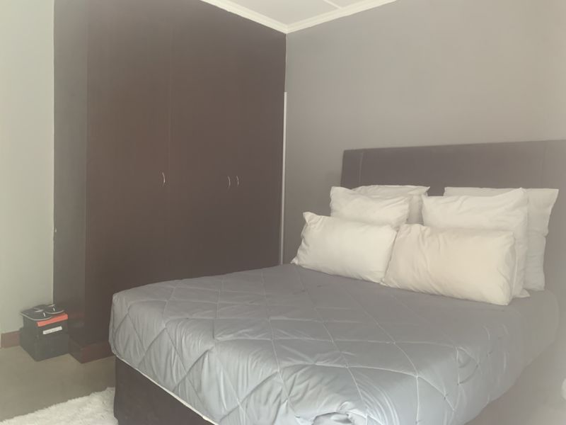 A bedroom featuring a dark wood built-in wardrobe and neutral wall finishes.