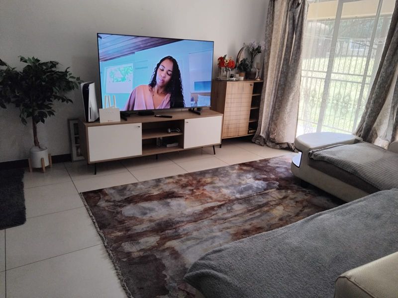 A comfortable living room featuring large format floor tiles and a sliding glass door with security gate providing access to the exterior.