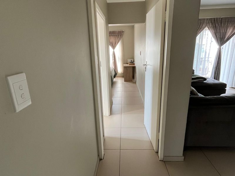 A functional hallway with tiled flooring connecting the living area to the bedroom spaces.