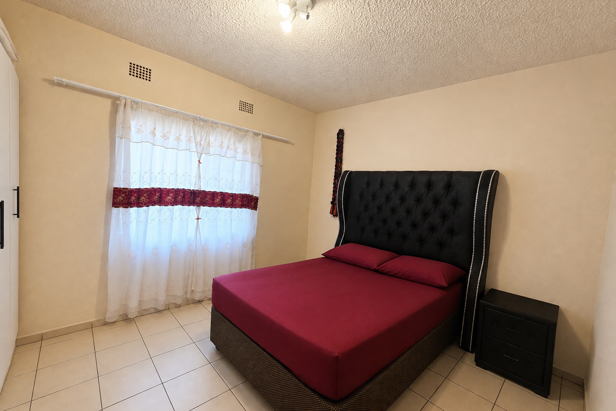 A bedroom featuring tiled flooring, a textured ceiling, and a built-in wardrobe, providing a functional and neutral living space.