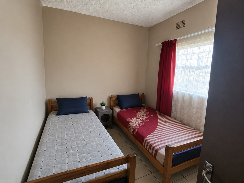 A functional bedroom featuring tiled flooring and a ventilation grille, providing a neutral space ready for personalization.