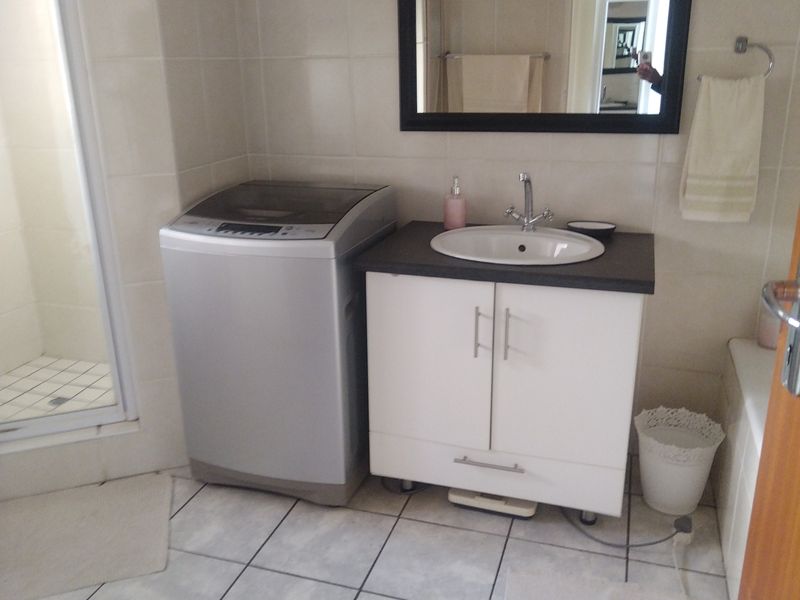 A functional bathroom featuring a vanity cabinet with basin, tiled walls and flooring, and a separate shower enclosure.