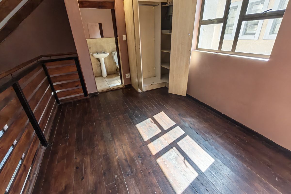 An empty bedroom featuring timber flooring, a built-in wardrobe, and direct access to an en-suite bathroom.