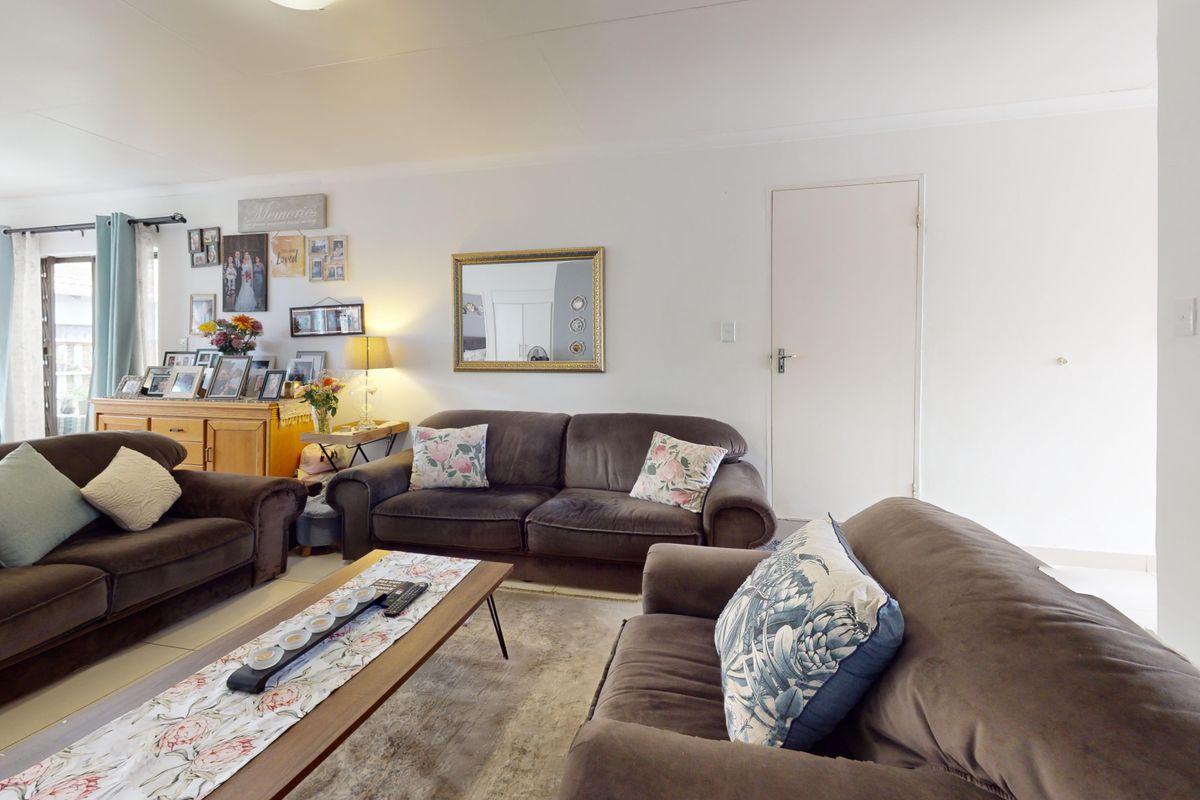 A spacious living room featuring neutral tiled flooring and access to an outdoor area through a sliding glass door.