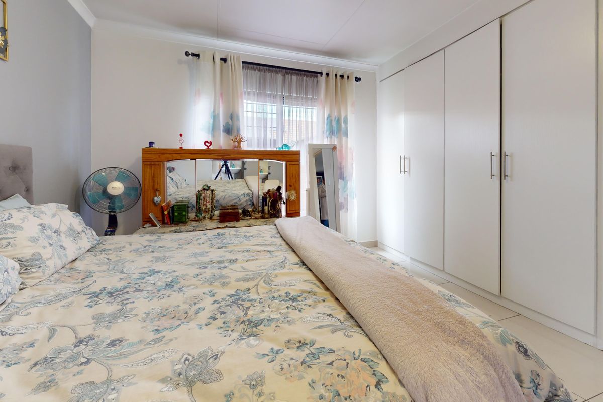 A well-maintained bedroom featuring neutral tiled flooring and ample storage space with floor-to-ceiling built-in cupboards.