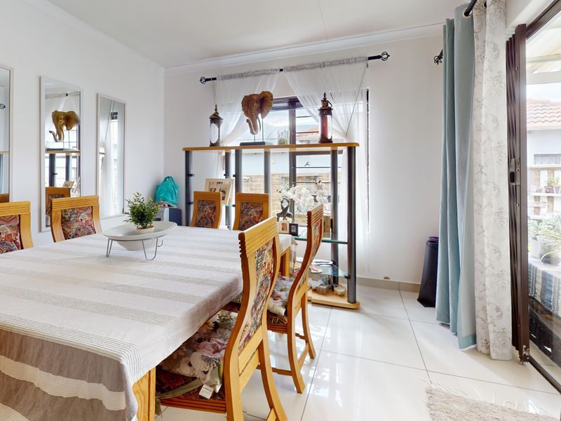 A bright dining room featuring large format floor tiles, cove cornicing, and a sliding glass door providing direct access to the outdoor area.