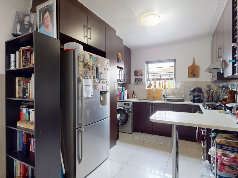 A functional kitchen featuring dark wood cabinetry, stone countertops, integrated appliances, and tiled flooring, offering a practical layout for daily meal preparation.