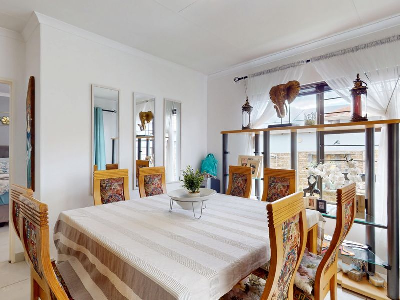 A bright dining room featuring tiled flooring and coved cornicing, with a view into the adjacent bedroom.