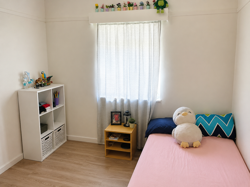 A clean and well-maintained bedroom featuring light-toned laminate flooring, a window with neutral curtains, and a classic picture rail.