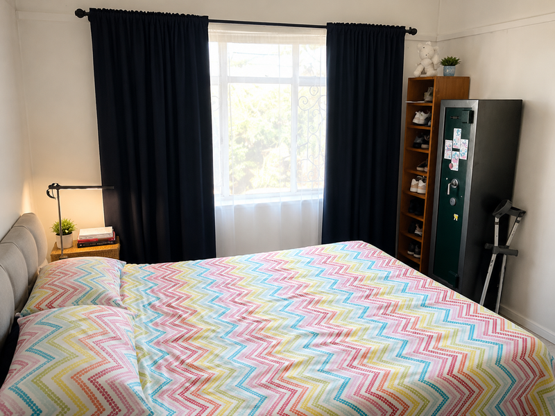 A well-lit bedroom featuring a central window with dark curtains and classic picture rail detailing.