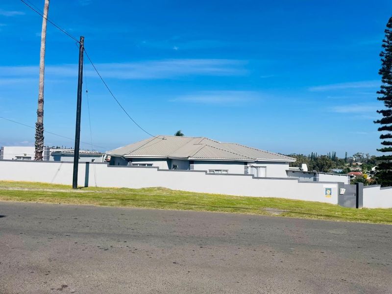 Street view of the property showing the perimeter wall, metal roof, and surrounding neighborhood context.