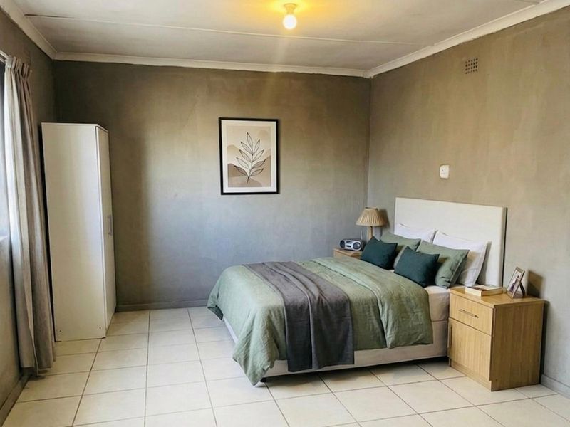 A bedroom featuring tiled flooring and plain walls, offering a functional space with basic finishes.