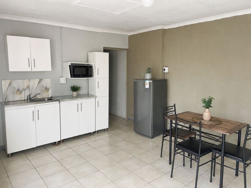 Open-plan kitchen and dining area featuring white cabinetry, tiled flooring, and a functional layout suitable for compact living.