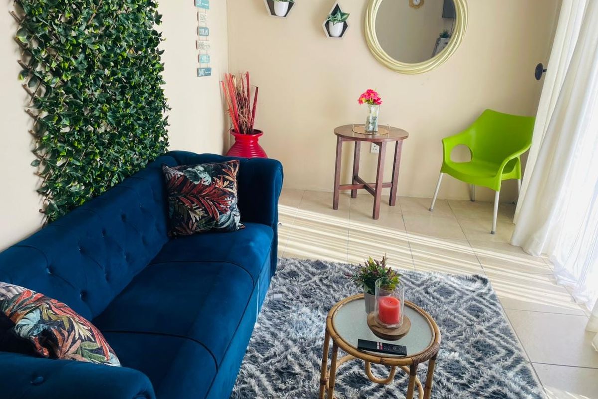 A bright living room area featuring tiled flooring and access to natural light through a large sliding glass door.