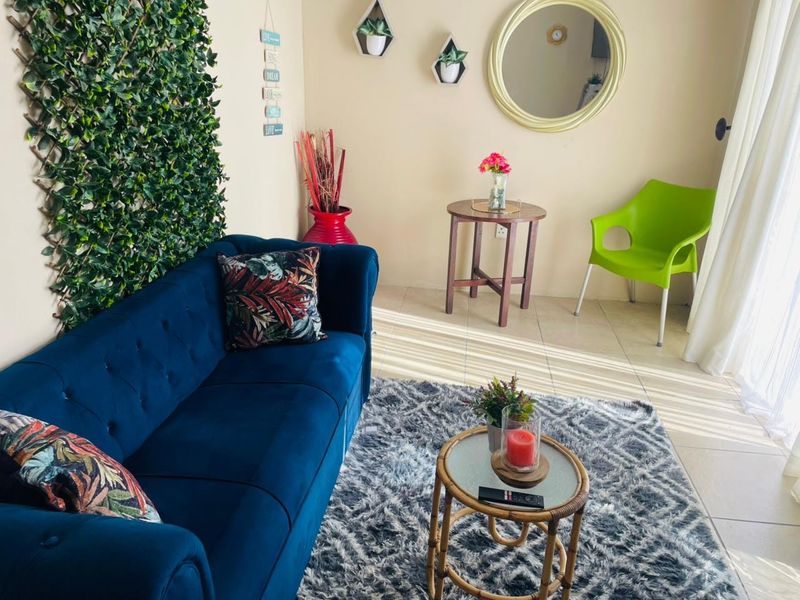 A bright living room area featuring tiled flooring and access to natural light through a large sliding glass door.