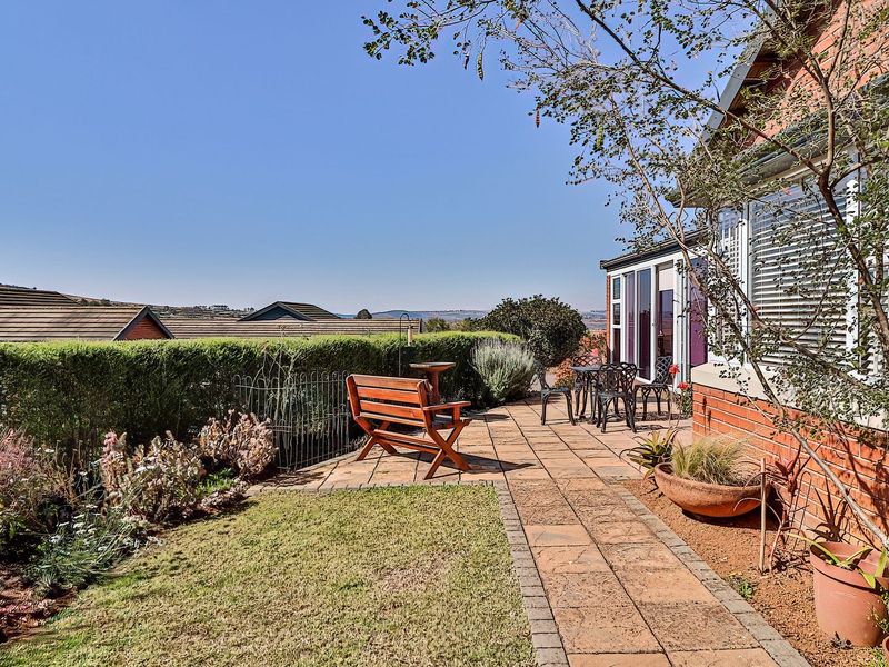 A well-maintained paved patio area adjacent to the house, featuring a landscaped garden border and scenic views of the surrounding neighborhood.