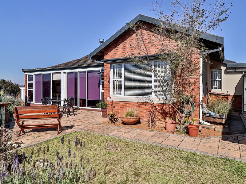 Rear view of the house featuring a brick facade, paved patio area, and large sliding glass doors leading into the living space.