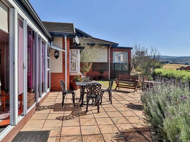 A paved outdoor patio area featuring a brick facade and large sliding glass doors, offering a pleasant space for outdoor relaxation.