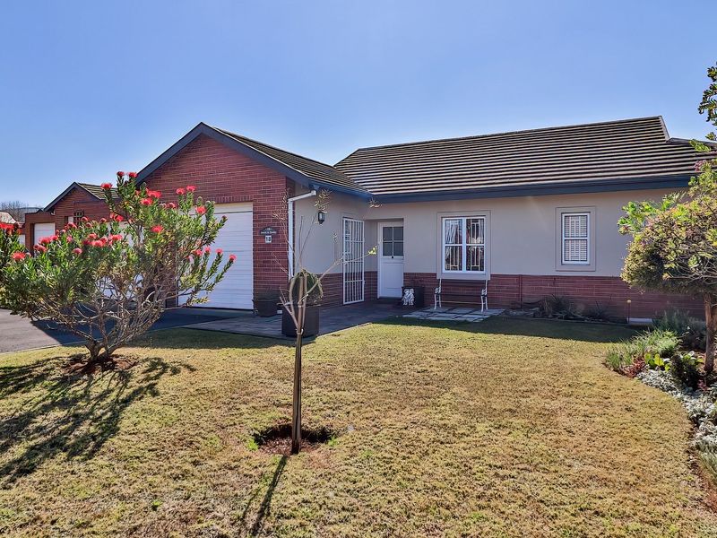 A well-maintained single-story brick home featuring a tiled roof, integrated garage, and a neat front garden with a paved driveway.
