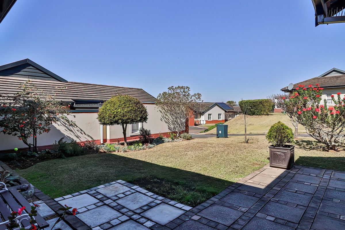 A well-maintained rear garden featuring a paved patio area, established lawn, and perimeter boundary walls, offering a pleasant outdoor space.