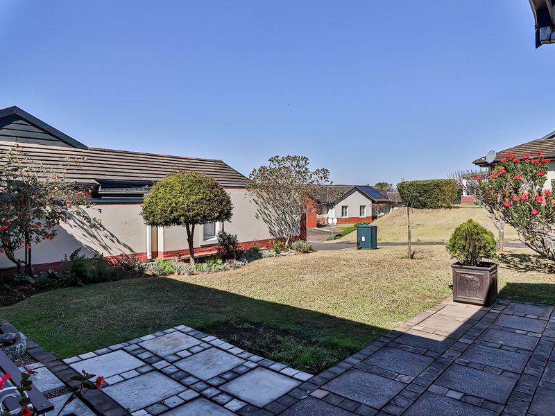 A well-maintained rear garden featuring a paved patio area, established lawn, and perimeter boundary walls, offering a pleasant outdoor space.