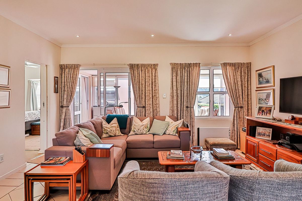 A comfortable living room featuring tiled flooring, recessed downlighting, and sliding glass doors that provide access to an adjoining patio area.
