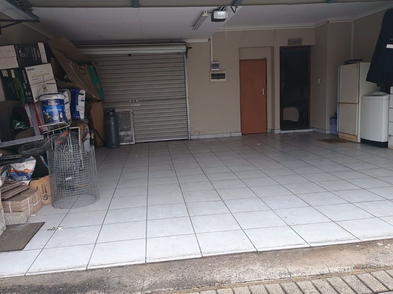 A spacious double garage featuring tiled flooring, a roll-up door, and direct access to the interior of the home.