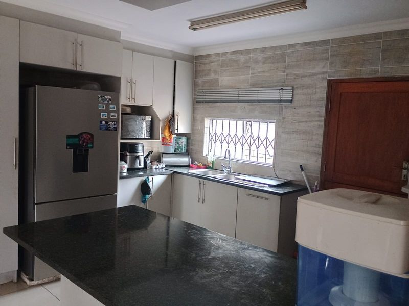 A functional kitchen featuring built-in cabinetry, granite countertops, a double basin sink, and tiled backsplash with a security-fitted window.
