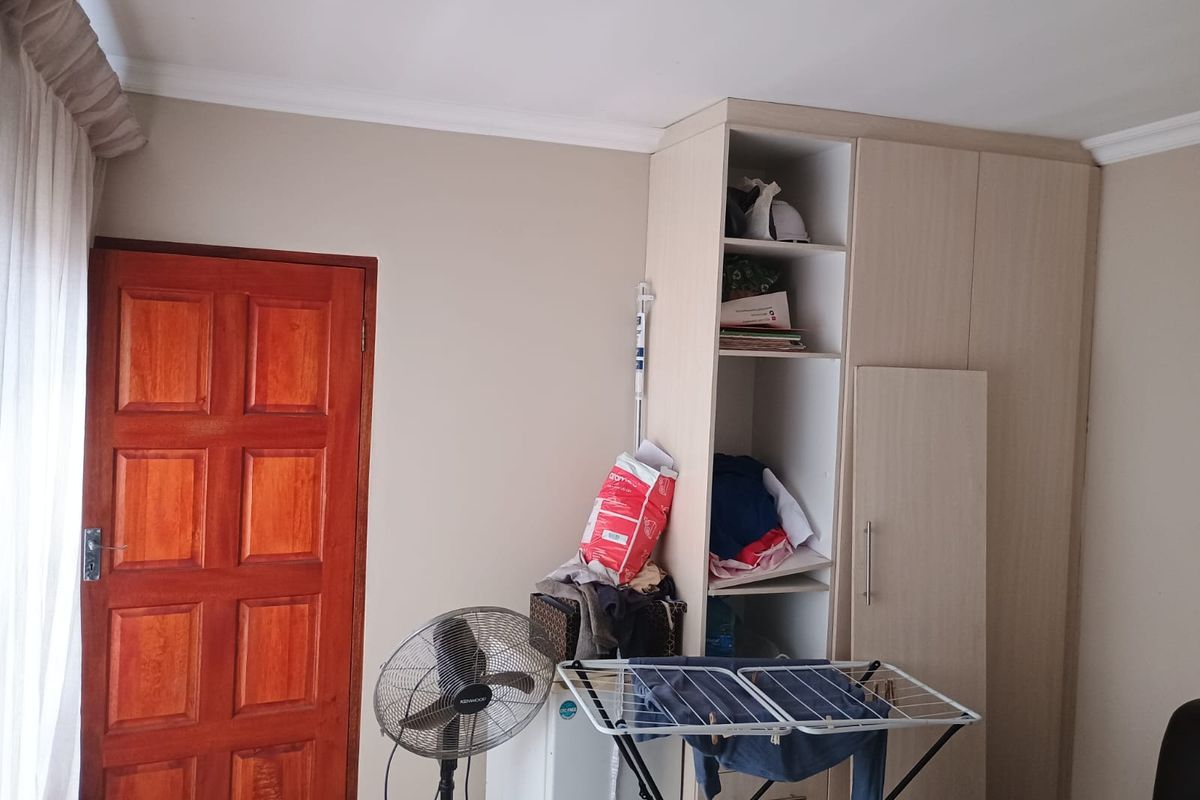 A bedroom featuring a built-in wardrobe with an open section and a solid timber door, finished with ceiling coving.