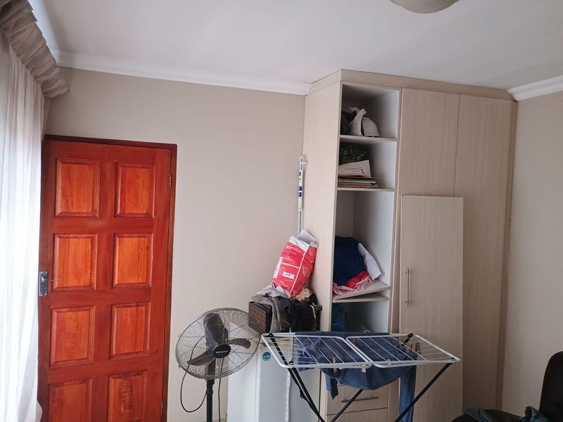 A bedroom featuring a built-in wardrobe with an open section and a solid timber door, finished with ceiling coving.