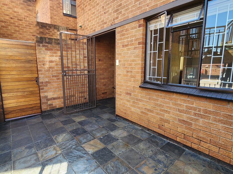 A private rear courtyard featuring durable face brick walls, a tiled patio surface, and secure gated access.