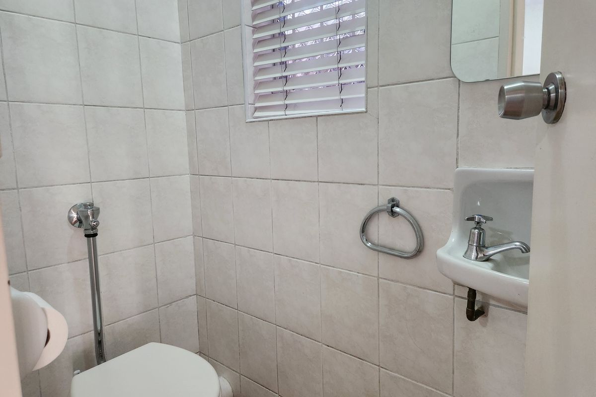 A compact guest bathroom featuring tiled walls, a wall-mounted basin, and a flush valve toilet.