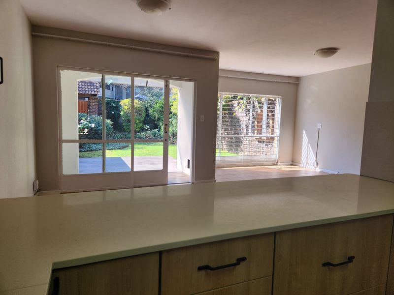 Open plan living area featuring kitchen cabinetry with stone countertops, tiled flooring, and sliding glass doors providing access to the rear garden.