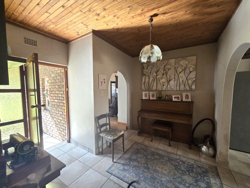 Entrance hall featuring a timber tongue and groove ceiling, ceramic tiled flooring, and an arched doorway leading to the living areas.