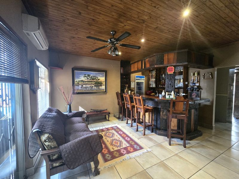 A dedicated bar area featuring a built-in timber counter, tiled flooring, and a rustic timber-clad ceiling with integrated lighting and air conditioning.