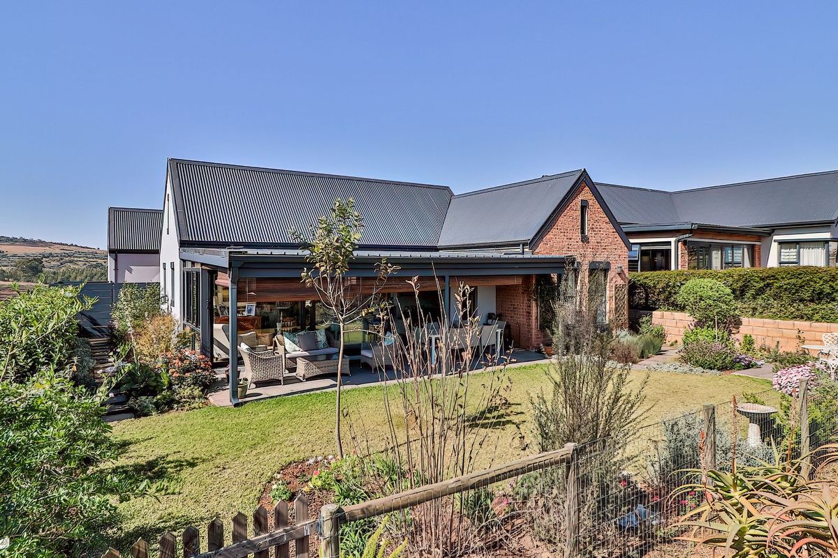 Rear view of the property featuring a covered patio, brick and metal roof construction, and a well-maintained landscaped garden.