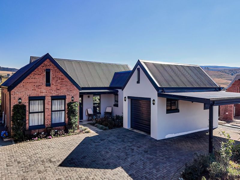 A well-maintained residential property featuring a brick and rendered facade, corrugated metal roofing, a paved driveway, and an integrated garage with a carport.