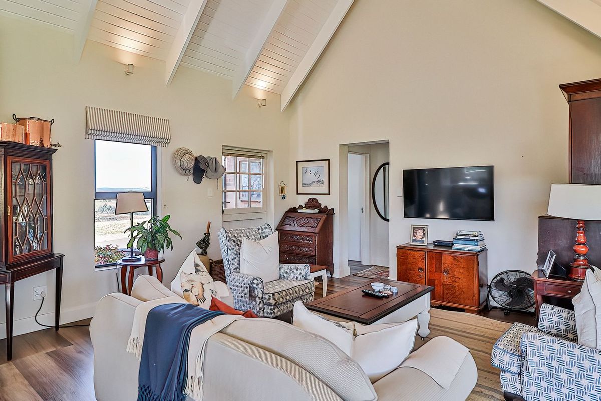 Spacious living room featuring a high vaulted ceiling with exposed timber beams, recessed lighting, and durable laminate flooring.