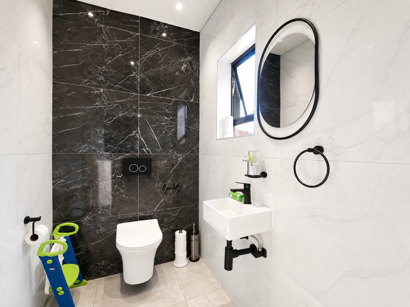 Modern guest bathroom featuring high-contrast black and white marble-effect tiling, wall-mounted sanitaryware, and sleek black fixtures.
