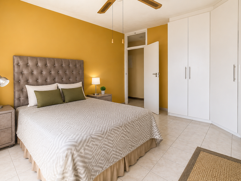 A well-maintained bedroom featuring tiled flooring, a ceiling fan, and ample built-in cupboard storage with a neutral color palette.