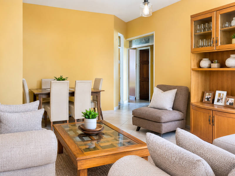 Open plan living and dining area featuring tiled flooring, a built-in wooden display cabinet, and warm yellow wall tones.