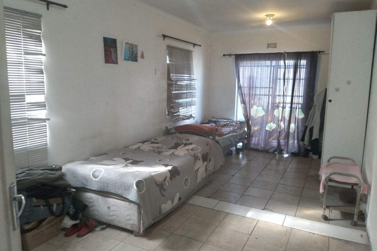 A bedroom featuring tiled flooring, a built-in cupboard, and access to an outdoor area via a sliding glass door.