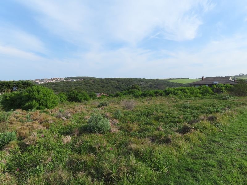 A scenic view of the vacant residential land featuring natural vegetation and surrounding landscape with distant hills.