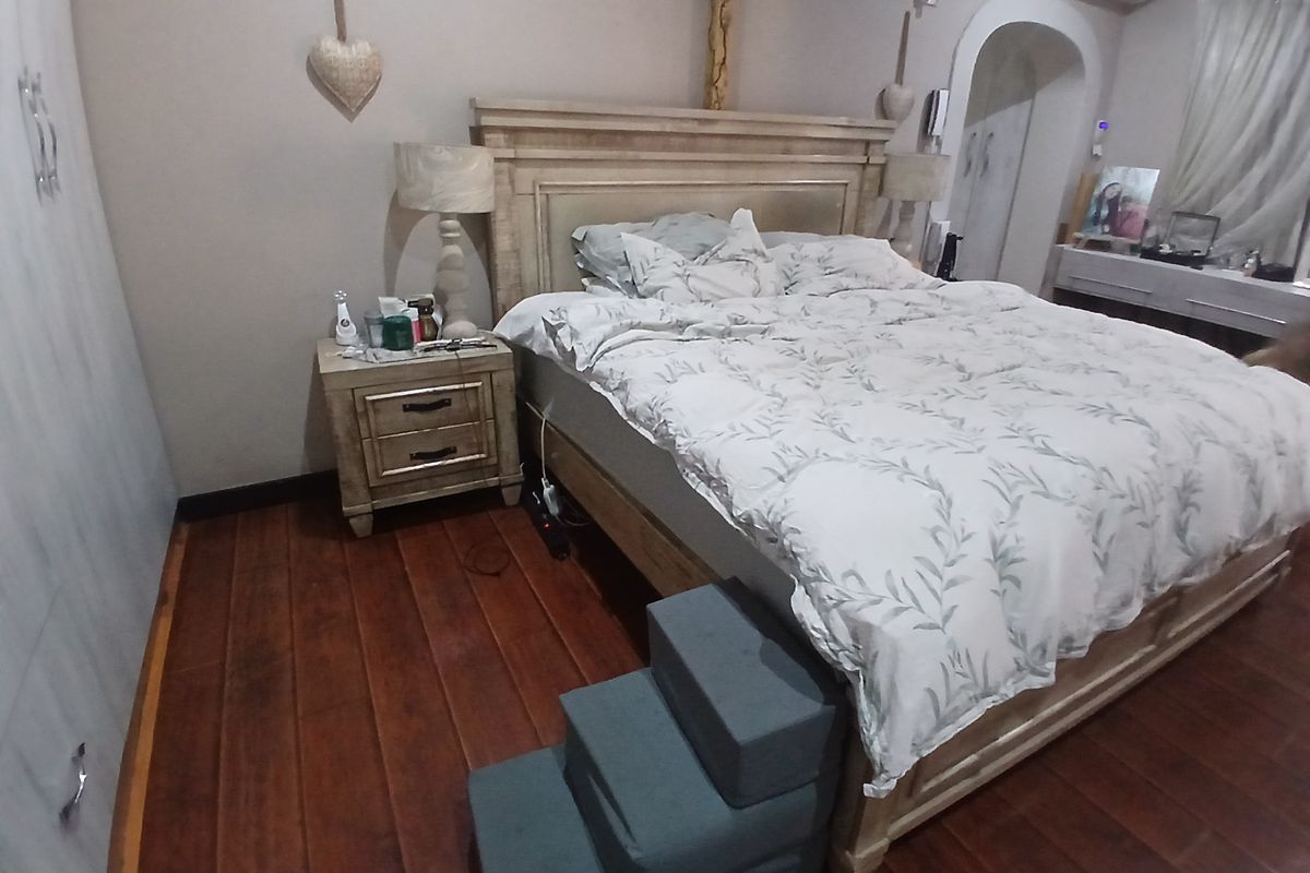 A bedroom featuring hardwood flooring, a built-in wardrobe, and a wall-mounted air conditioning unit.