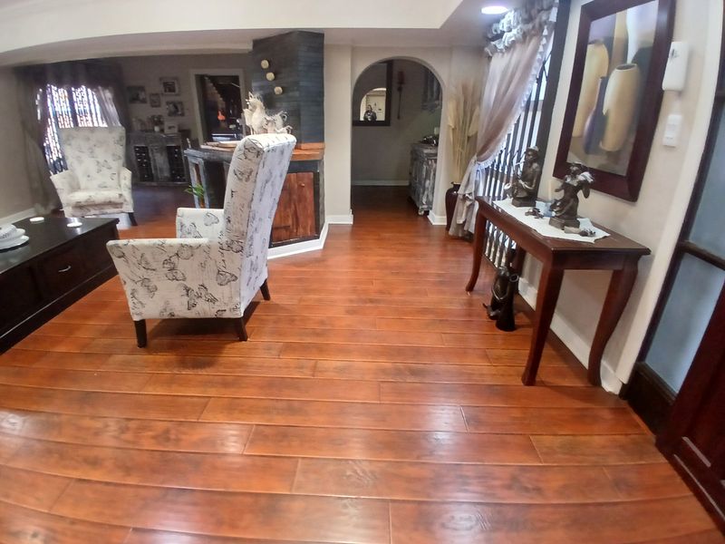 Spacious living area featuring warm-toned laminate flooring, a distinctive stone-clad feature pillar, and an elegant arched entryway leading to adjacent rooms.