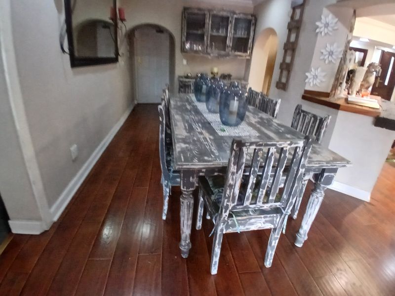 A dining room featuring polished hardwood flooring, an arched doorway, and built-in cabinetry, providing a functional space for family meals and entertaining.