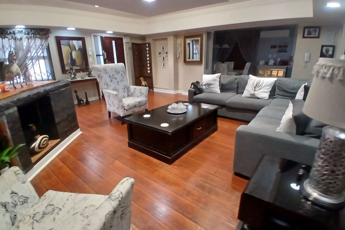 Spacious living room featuring hardwood flooring, recessed ceiling lighting, and a built-in fireplace, creating a warm and inviting atmosphere.