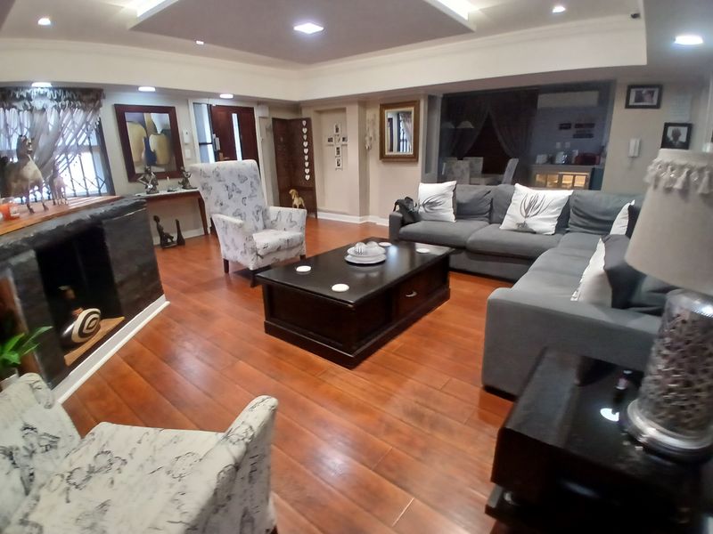 Spacious living room featuring hardwood flooring, recessed ceiling lighting, and a built-in fireplace, creating a warm and inviting atmosphere.