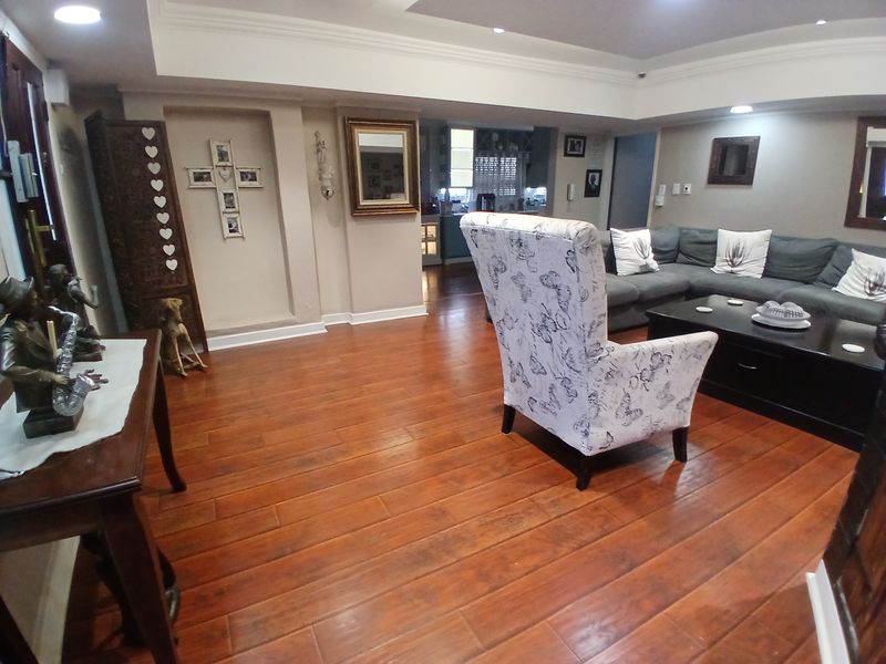 Spacious living room featuring warm hardwood flooring, recessed lighting, and a decorative cove ceiling, creating a comfortable and inviting atmosphere.