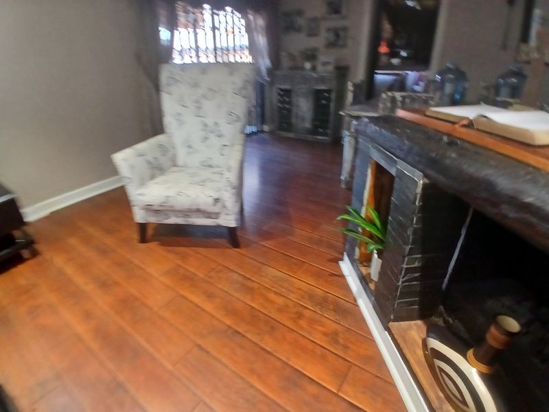 A living room area featuring warm-toned laminate flooring and a built-in fireplace structure.